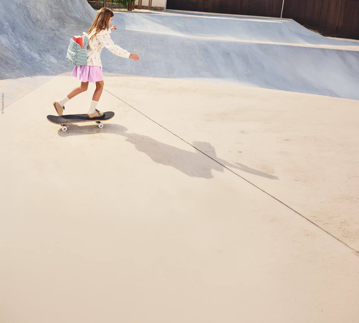 Mädchen af Skateboard mit Schulrucksack
